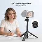 The girl holding a pen is using the NEEWER DT001 All-in-One Extendable Selfie Stick Tripod to take notes at her desk.
