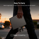 A man is holding the NEEWER MS047 Microphone Stand Tray with Crab Clamp in his hand.